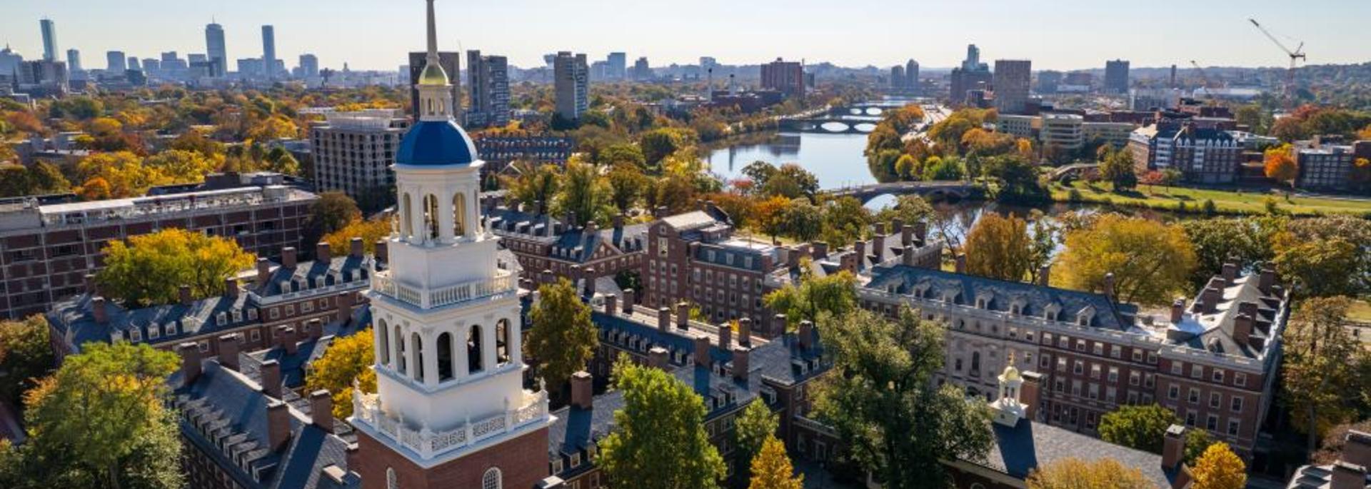 A bird's eye photo of the top of Lowell House during the fall with the Charles River in the background.