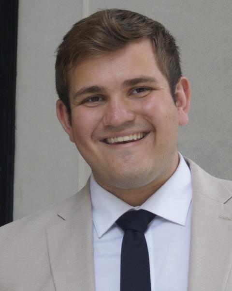Man wearing a tan jacket and smiling
